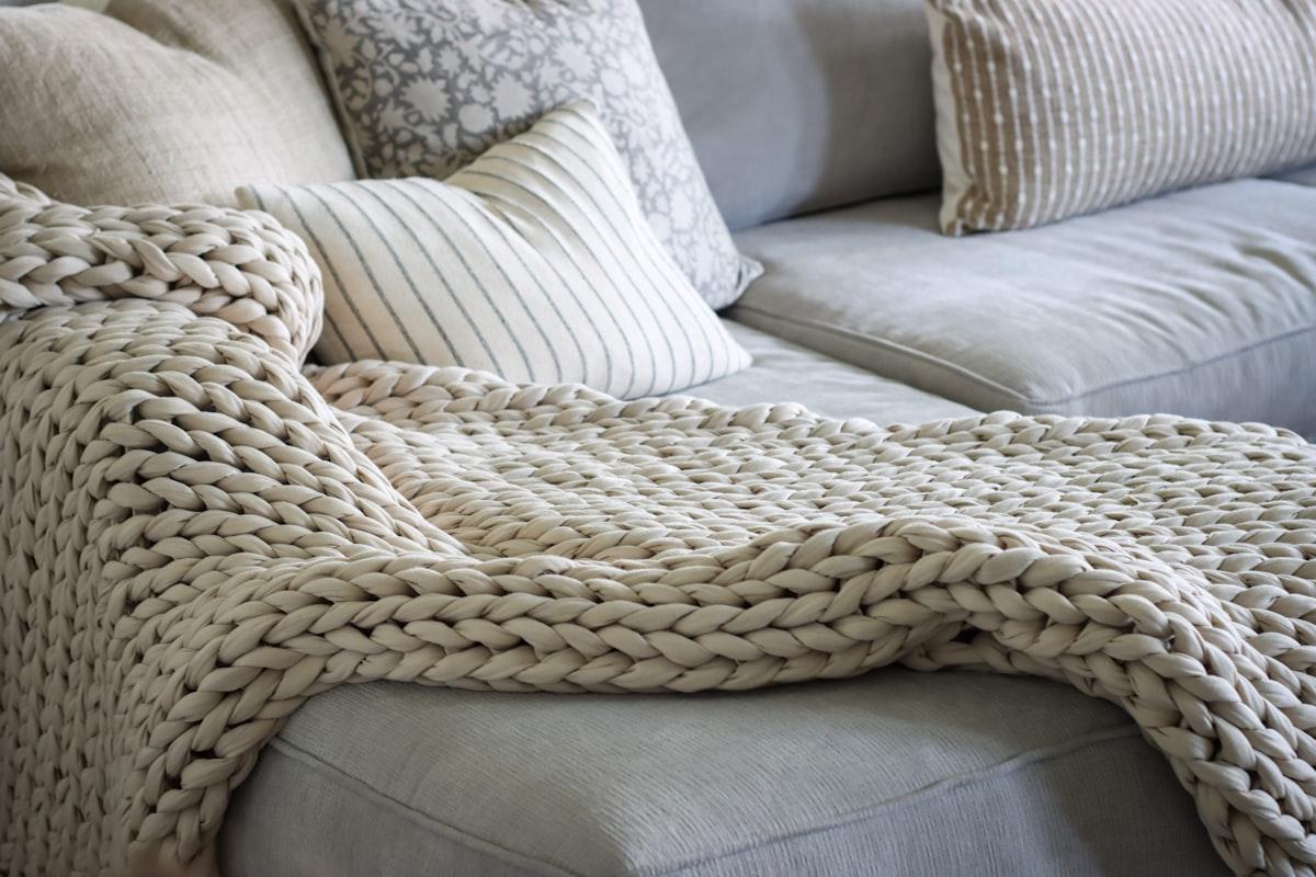 Chunky-knit cream throw blanket draped over a sofa
