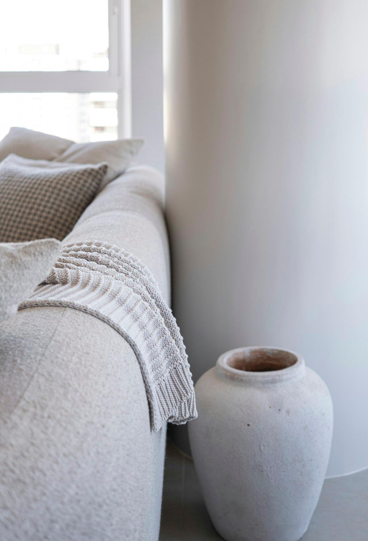 Neutral-tone cushions and a knit throw on a sofa
