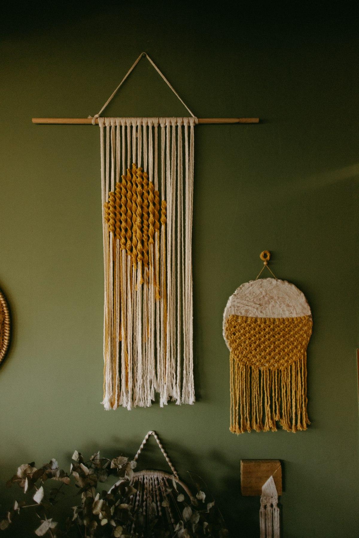 Macrame wall hangings in cream and mustard tones on a green wall