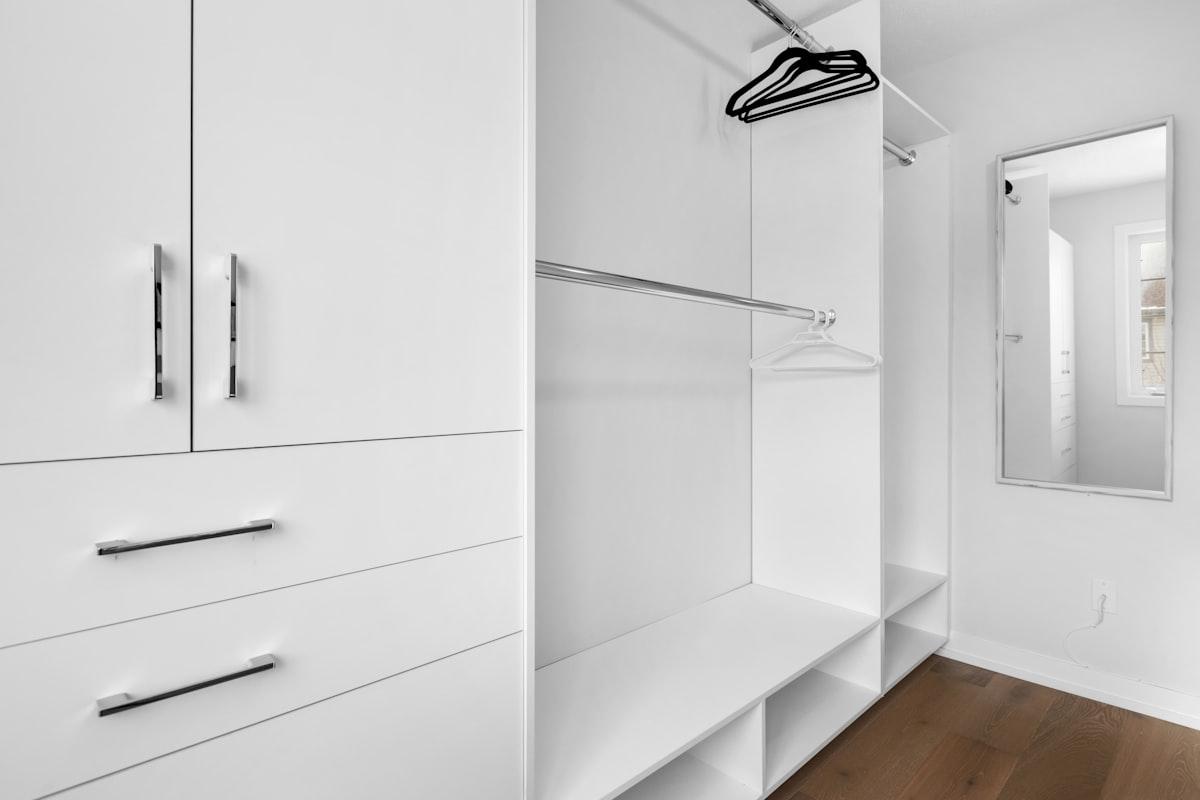 Organized white built-in dressing closet with hanging rail and cubbies