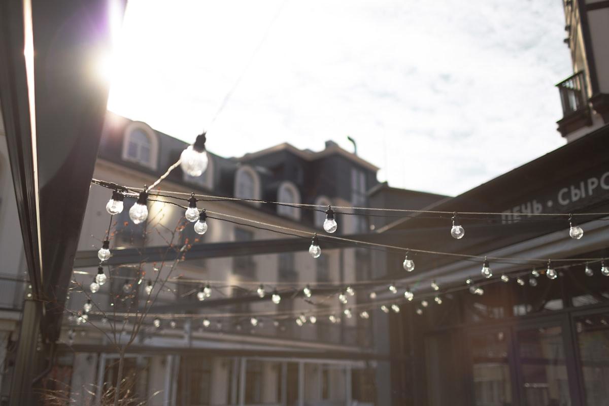 String lights strung outdoors over a terrace in bright daylight