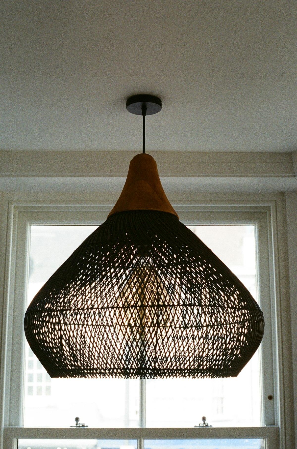 Woven rattan pendant light hanging in front of a window