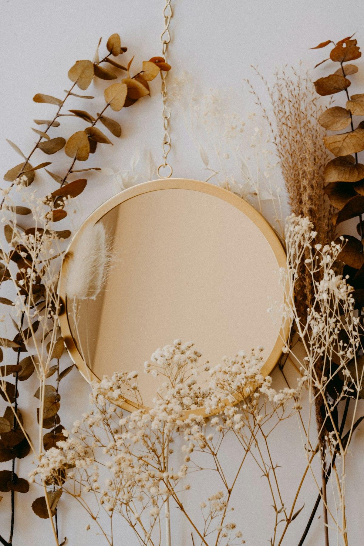 Round brass-framed mirror styled with dried flowers