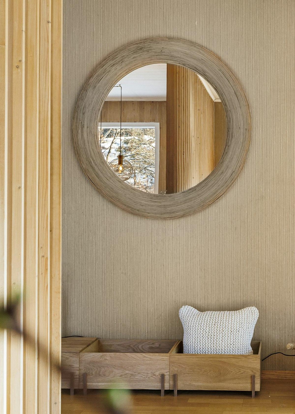 Large round wall mirror reflecting a bright room