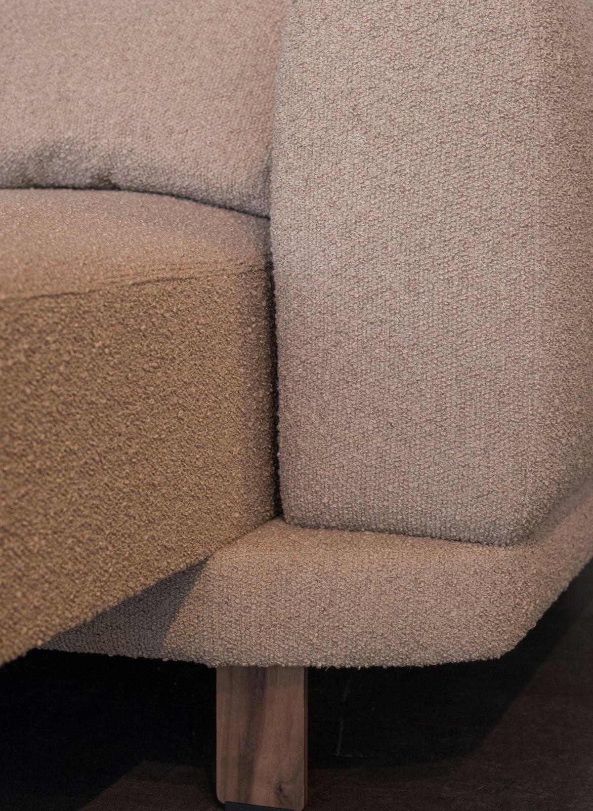 Beige bouclé sofa with a solid light wood leg