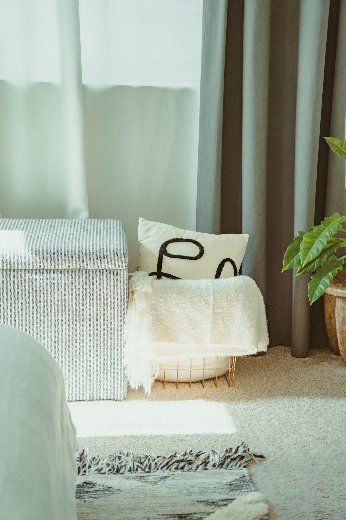 Striped storage ottoman with a blanket next to a window