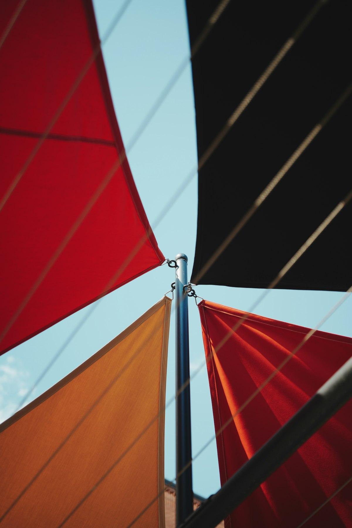 Triangular fabric shade sails stretched against a clear blue sky