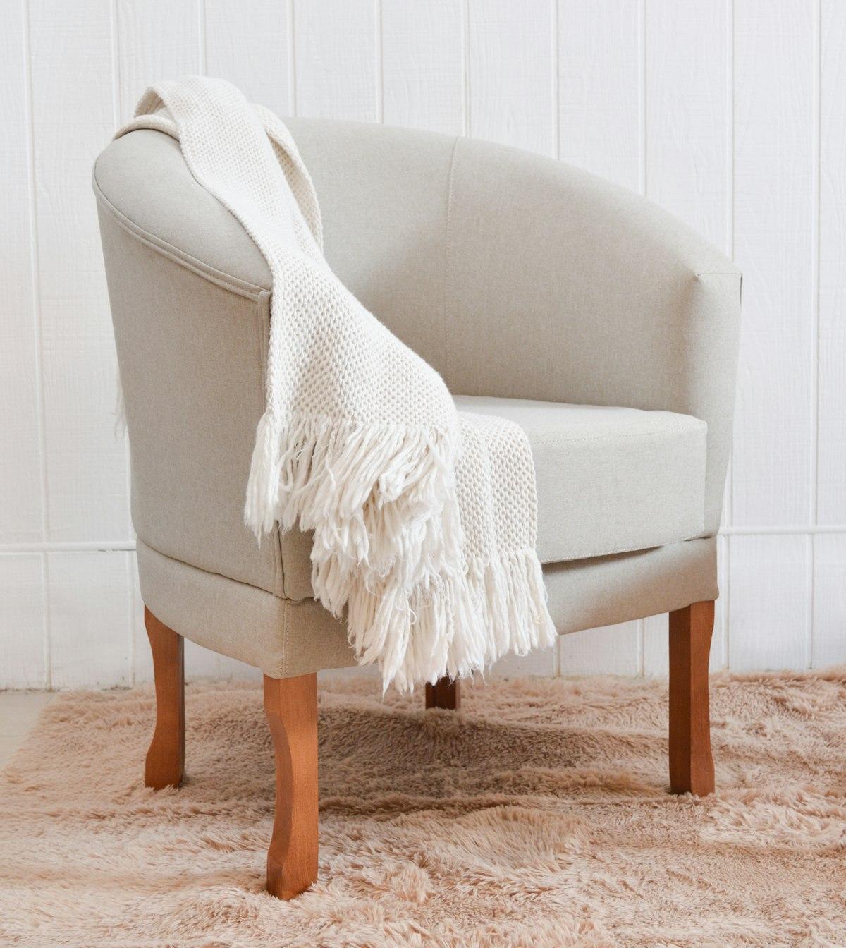 Cream chunky-knit wool throw draped over an armchair